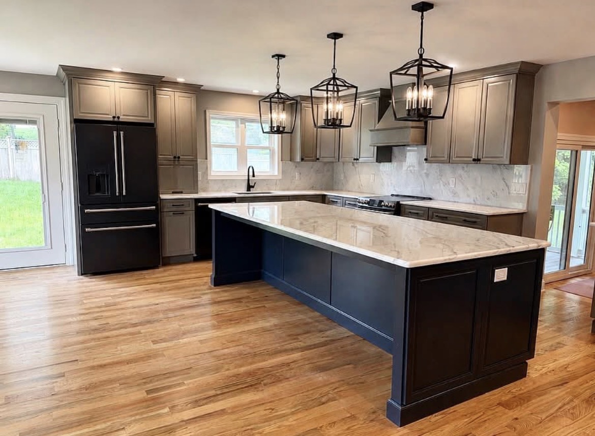 Finished kitchen remodel by B&T — navy island, marble counters and lantern pendants